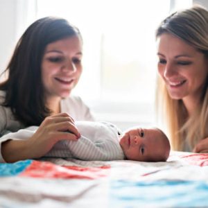 The Two friend girl with a newborn baby on bed
